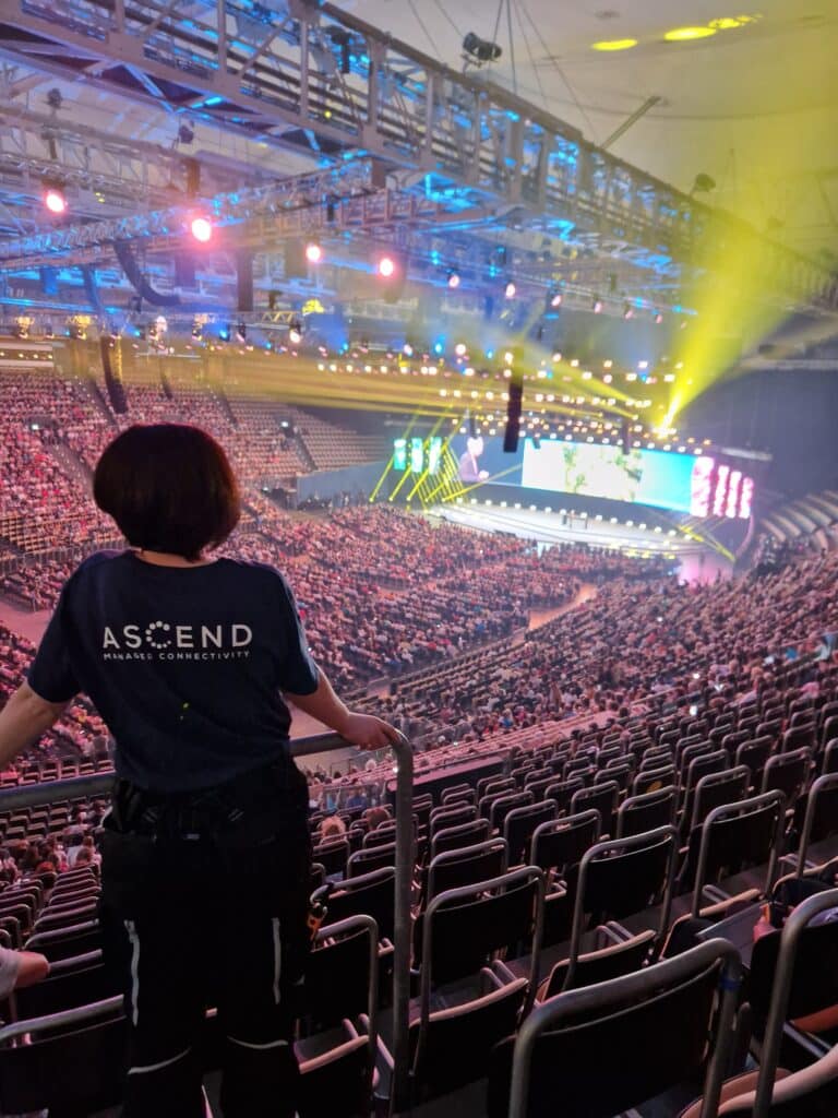 Kollegin des Ascend Teams steht vor Menschenmenge in Olympiahalle bei Großveranstaltung