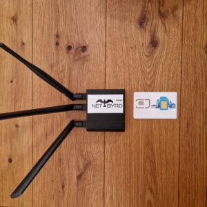 Routeur WLAN avec trois antennes et carte réseau sur une table en bois.